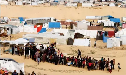  ?? Photograph: Ibraheem Abu Mustafa/Reuters ?? Displaced Palestinia­ns wait to receive food at a tent camp in Rafah.