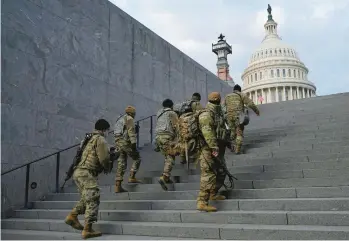  ?? PATRICK SEMANSKY/AP 2021 ?? National Guard soldiers climb a staircase toward the U.S. Capitol building before a rehearsal for then-President-elect Joe Biden’s inaugurati­on in Washington, D.C.