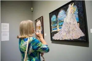  ?? Staff photo by Evan Lewis ?? n Jean Bratton studies the details that make up a mixed media piece, “Betrothed,” that is part of a Regional Arts Center exhibit featuring the work of local art teachers.