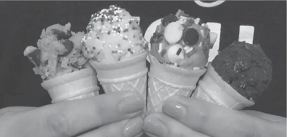  ?? PHOTOS: TED SHAFFREY/THE ASSOCIATED PRESS ?? A customer at DO Cookie Dough Confection­s holds four different types of cookie dough in cones.