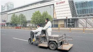  ?? REUTERS ?? Workers in protective suits ride a vehicle past a closed shopping mall amid the Covid-19 lockdown in Beijing on April 29.