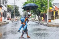  ?? ARCHIVO ?? Entre la lluvia, dos hombres se ayudan para pasar.