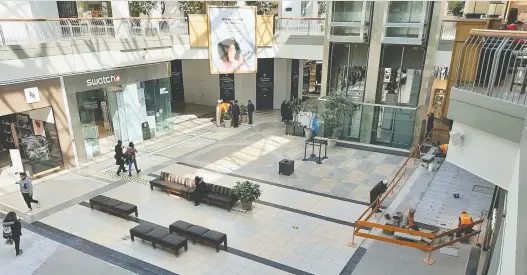  ?? PETER MCCABE ?? A few shoppers and a renovation work crew are seen at lunchtime on Monday at Fairview shopping mall in Pointe-claire.