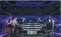  ?? CHEN CHENG / XINHUA ?? Visitors look at Ford’s SUV model Edge at an auto show in Chongqing.