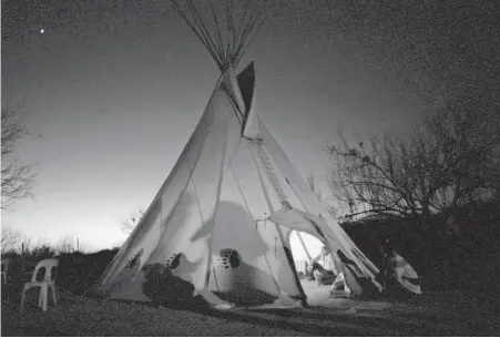  ??  ?? Members of the Native American Church of North America prepare for a prayer meeting in Mirando City, Texas. The church blends Native American beliefs and Christiani­ty, but doesn’t have formal buildings.