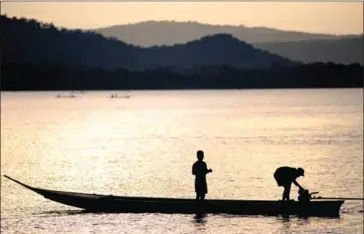  ?? MRC ?? A fisherman starts his boat engine as his son looks on along the Mekong River in Luang Prabang, Laos.