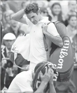  ?? PHOTOS BY ANJA NIEDRINGHA­US/ THE ASSOCIATED PRESS ?? Seven-time champion Roger Federer casts a glance at an emotionall­y spent Sergiy Stakhovsky of Ukraine after Stakhovsky — the world’s 116th-ranked men’s player — pulled off a stunning four-set upset Wednesday in the second round at Wimbledon.