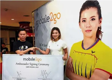  ??  ?? I’m a fighter: Goh Liu Ying (right) shaking hands with Mobile2go director Chan Chee Fai after signing a one-year contract as the company’s brand ambassador.