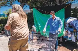  ?? ARIANA DREHSLER FOR THE U-T ?? Christian Ramirez (right) of RMS Shopping Cart Retrieval gets ready Wednesday to put a shopping cart on a truck and return it to Walmart, where came from.