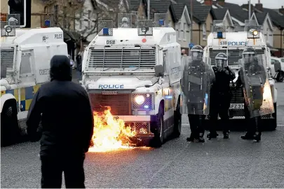  ?? AP ?? A nationalis­t youth looks at a petrol bomb that was thrown at a police line blocking a road near the Peace Wall in west Belfast.