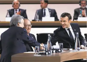  ?? Etienne Laurent / AFP / Getty Images ?? French President Emmanuel Macron (right) greets U.N. Secretary General Antonio Guterres at the opening of the One Planet Summit in Paris.