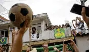  ?? AP ?? People watch the funeral procession of Pelé pass by the home of Pelé’s mother, where members of his family stand on the balcony, in Santos, Brazil, on Tuesday.