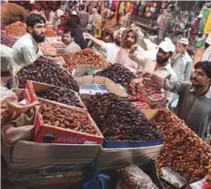  ?? AFP ?? People buy dates at a market ahead of Ramadan in Karachi on Wednesday. Residents are bracing for a weeklong heatwave.