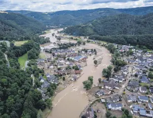  ??  ?? The Ahr river flows past houses destroyed by floods in Insul, Germany, July 15, 2021.