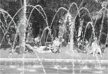  ?? PAUL WHITE/AP ?? Spain simmers: People sit by a fountain in a park in Madrid, Spain, on Saturday. People in Spain are trying to stay as cool as possible as forecasts showed weekend temperatur­es could rise above 104 degrees in large parts of the Iberian Peninsula. The heat scorched south-central Spain on Saturday before spreading east over the next two days.