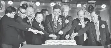  ??  ?? Pelly (front, fifth right) joins Sibu Mandarin Lions Club president Thomas Tong on her left and other senior Lions in cutting the cake.