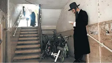  ?? ODED BALILTY/AP ?? Ultra-Orthodox Jews observe social distancing during a morning prayer next to their houses last week in Bnei Brak, Israel. Amid the coronaviru­s pandemic that’s led to a new lockdown in the country, synagogues are limited to 20 people.