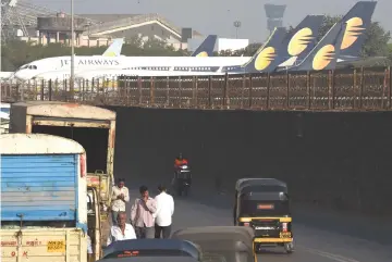  ??  ?? Vehicles ply along a road adajacent to Jet Airways aircraft parked at the airport in Mumbai on April 10. Creditors in March injected US$218 million of “immediate funding support” into Jet as part of a debt resolution plan. – AFP photo