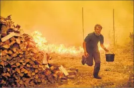  ?? Noah Berger AFP/Getty Images ?? ALEX SCHENCK tries to guard his Lake County home this month from the Ranch fire — part of the Mendocino Complex, which has burned 364,145 acres.