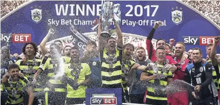  ?? AP ?? Huddersfie­ld Town’s Mark Hudson lifts the trophy after winning the Sky Bet Championsh­ip play-off final at Wembley Stadium, London, yesterday. Huddersfie­ld Town will play in England’s top division for the first time in 45 years after beating Reading 4-3...