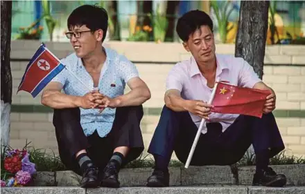  ?? AFP PIC ?? Two men holding North Korean and Chinese flags near Kim Il-sung Square in Pyongyang yesterday.