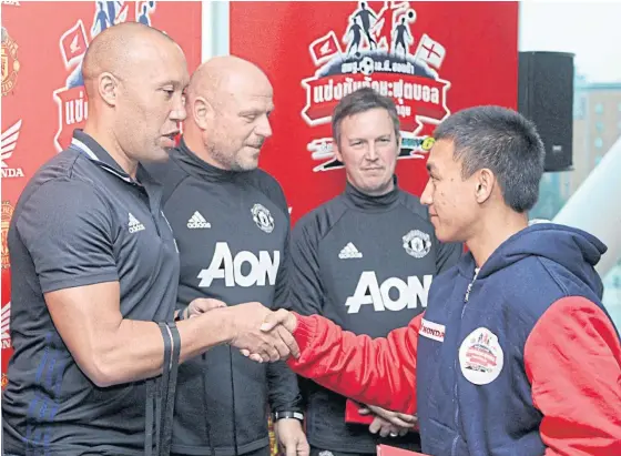  ??  ?? A Thai player receives a certificat­e from former Manchester United defender Mikael Silvestre at Old Trafford.