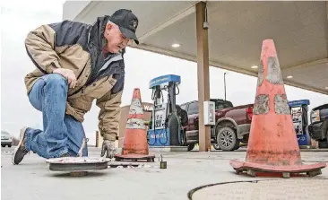  ?? [PHOTOS BY CHRIS LANDSBERGE­R, THE OKLAHOMAN] ?? Fuel Specialist Justin Lankford of the Oklahoma Corporatio­n Commission inspects a fuel delivery receptacle at a retailer’s location in southwest Oklahoma City.