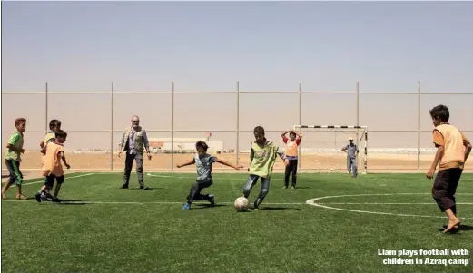 ??  ?? Liam plays football with children in Azraq camp