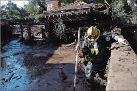  ?? MARCIO JOSE SANCHEZ/AP PHOTO ?? Alex Broumand of the Montecito Fire Department walks in mud in front of homes damaged from storms in Montecito, Calif., on Thursday. Rescue workers slogged through knee-deep ooze and used long poles to probe for bodies.