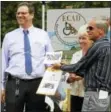  ??  ?? Steven Sadlowski, Director of Planning and Community Developmen­t, joins Winsted Mayor Althea Candy Perez in presenting the official building permit to ECAD co-founder, Dale Picard, during groundbrea­king ceremonies for ECAD’s new Canine Education and...