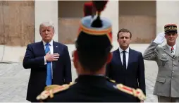  ?? (Yves Herman/Reuters) ?? FRENCH PRESIDENT Emmanuel Macron and US President Donald Trump listen to their countries’ national anthems as they review troops during a welcoming ceremony at the Invalides in Paris yesterday.