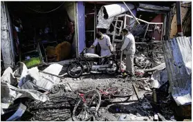  ?? MASSOUD HOSSAINI / ASSOCIATED PRESS ?? Two men examine the wreckage Monday left by a suicide car bomb that killed at least two dozen people in western Kabul, Afghanista­n, and injured at least 42 more. One official put the number of dead at 38.