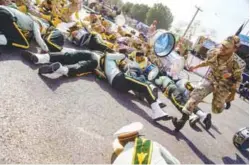  ??  ?? A soldier runs past injured comrades at the scene of the attack in Ahvaz on Saturday.