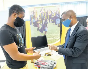  ?? RICARDO MAKYN/CHIEF PHOTO EDITOR ?? National goalkeeper Akeem Chambers, who is also a student of The Mico University College, receives a laptop and a bag from principal Dr Asburn Pinnock during the launch of the institutio­n’s students’ COVID-19 relief programme yesterday. The event took place at the school’s campus on Marescaux Road in Kingston.