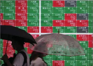  ?? (AP/Shuji Kajiyama) ?? People walk past an electronic board showing Japan’s stock prices at a securities company in Tokyo on Friday. Asian shares were mostly higher on Friday amid a deluge of news about the economy, interest rates and corporate profits.