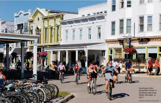  ?? ERIC SEALS Detroit Free Press/TNS ?? Vacationer­s bike along Main Street in downtown Mackinac Island, Michigan, in July 1.