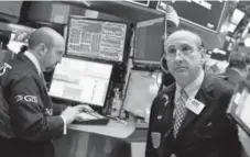  ?? Richard Drew, The Associated Press ?? Specialist James Denaro, left, and trader Andrew Silverman work Thursday on the floor of the New York Stock Exchange.