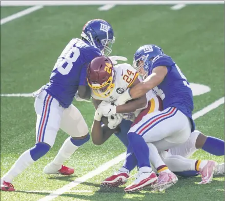  ?? JOHN MINCHILLO - THE ASSOCIATED PRESS ?? Washington Football Team running back Antonio Gibson (24) is tackled by New York Giants’ Blake Martinez (54) and Montre Hartage (18) during the second half of an NFL football game Sunday, Oct. 18, 2020, in East Rutherford, N.J.