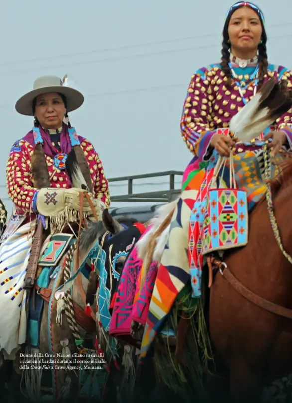  ?? ?? Donne della Crow Nation sfilano su cavalli riccamente bardati durante il corteo iniziale della Crow Fair a Crow Agency, Montana.