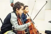  ?? JULIEN MIGNOT FOR THE NEW YORK TIMES ?? Amine Jerbi, left, a Tunisian during a cello lesson at a music academy outside Paris that loans instrument­s to children.