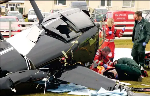  ?? Pictures: Scotland Charity Air Ambulance/pa Wire ?? „ Emergency personnel help the injured pilot after his helicopter crashed yesterday morning at Perth Airport.