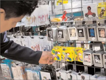  ?? Michael Nagle/Bloomberg ?? A shopper browses fidget spinners displayed for sale by a street vendor in New York City. The fidget spinner is a toy that sits like a propeller on a person's finger, with blades that spin around a bearing.