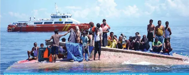  ?? ?? ACEH: Rohingya refugees wait to be rescued from the hull of their capsized boat as a National Search and Rescue Agency vessel approaches on March 21, 2024. — AFP photos