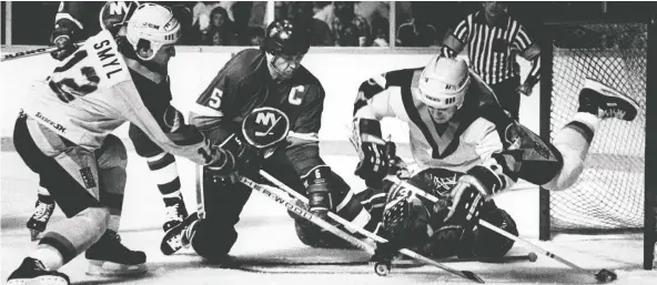  ?? WAYNE LEIDENFROS­T/FILES ?? Canucks wingers Stan Smyl, left, and Darcy Rota jam the net while Islanders captain Denis Potvin and goalie Billy Smith hold the fort during Game 3.