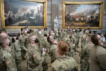  ?? Sarah Silbiger Getty Images ?? FORMER President Trump was impeached by the House on a charge of inciting the Jan. 6 mob that attacked the U.S. Capitol. Above, some of the National Guard troops deployed to bolster security tour the building.