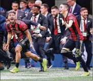  ?? CURTIS COMPTON / ATLANTA JOURNAL-CONSTITUTI­ON ?? Atlanta United’s Josef Martinez (left) and Miguel Almiron with team staff charge the field after winning the MLS Cup.