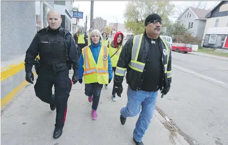  ?? KEVIN KING ?? Winnipeg police Const. Jeff Boehm, left, walks with a group lead by Bear Clan Patrol organizer James Favel. Since 2015, Favel and his team have evolved the patrol’s mandate — upgrading to become a welcome wagon, resource service, cleanup crew, conflict mediator and youth organizati­on.