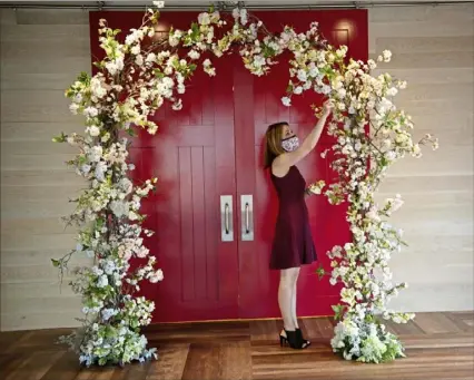  ?? Pam Panchak/Post-Gazette ?? Alison Kwiatkowsk­i, director of sales at Roost in Downtown, arranges a wedding arch with flowers by Green Sinner on June 5. The event venue has partnered with other wedding businesses to create smaller receptions that meet COVID-19 guidelines.