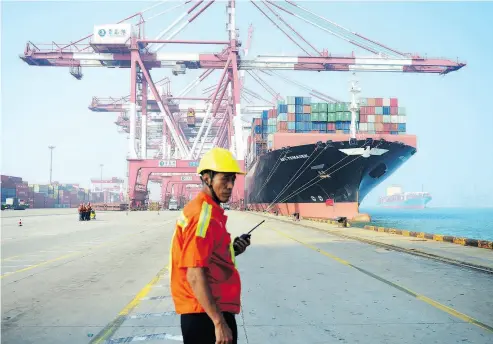  ?? STR / AFP / GETTY IMAGES FILES ?? A worker looks on as a cargo ship is loaded at a port in Qingdao, China, in July 2017. Canada will pursue a deeper trading relationsh­ip with China, Prime Minister Justin Trudeau said on Tuesday despite a clause in the USMCA that places restrictio­ns on free-trade agreements with “non-market” countries.