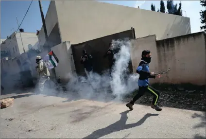  ?? PICTURE: REUTERS ?? A Palestinia­n protester runs for cover from tear gas fired by Israeli troops during clashes in the West Bank village of Kofr Qadom on Friday.